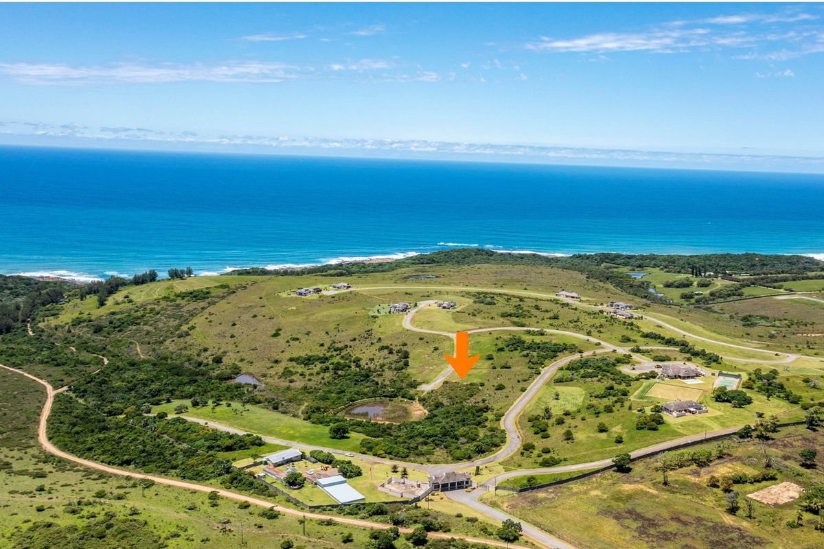 Aerial view of a vacant residential plot situated in a coastal estate, featuring scenic ocean views and established road access.
