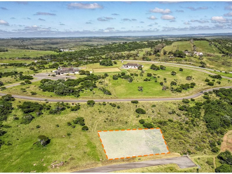 Aerial view of a vacant residential plot in a scenic estate, featuring natural landscape and convenient road access.