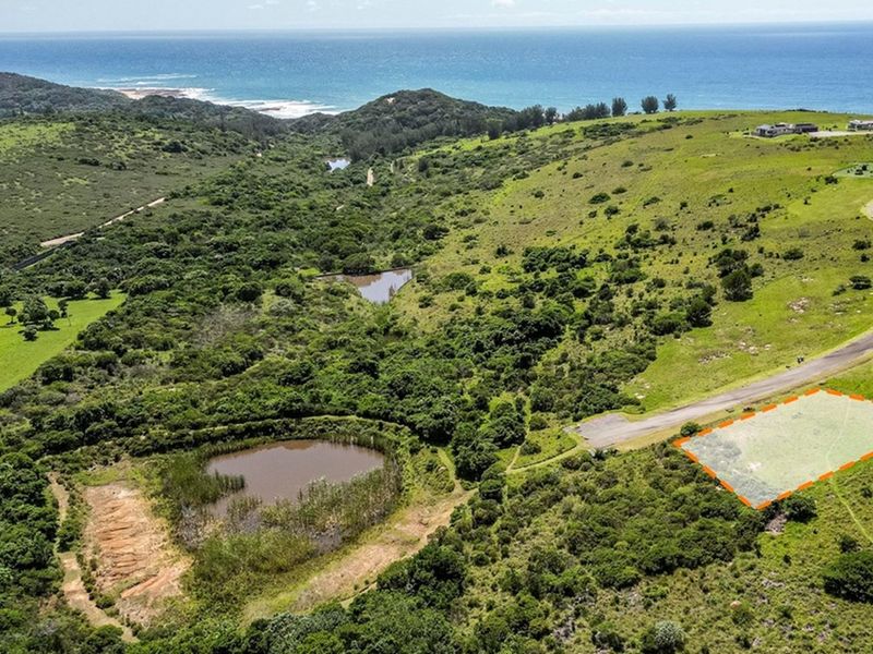 Aerial view of a vacant residential plot featuring coastal landscape, natural vegetation, and convenient paved road access.
