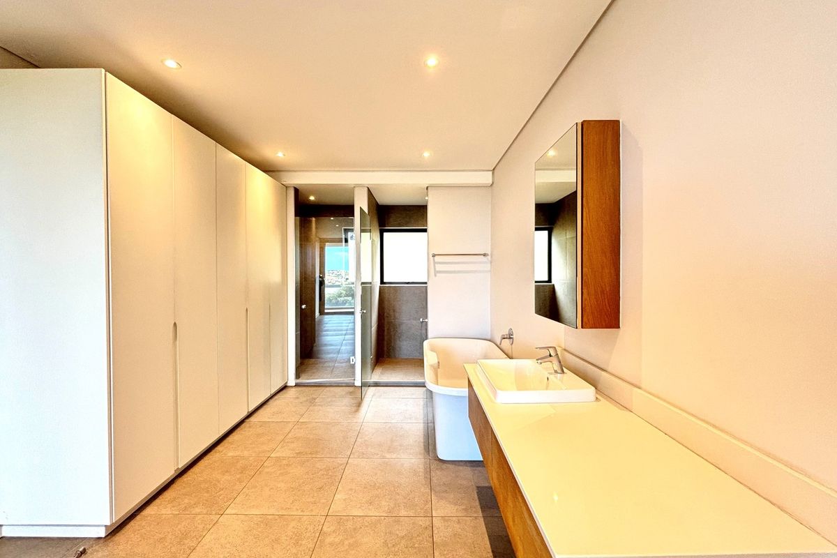 Modern bathroom featuring a sleek vanity with integrated basin, freestanding bathtub, recessed lighting, and extensive built-in cabinetry for ample storage.