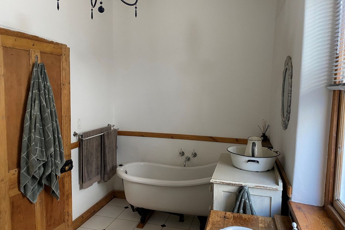 A bathroom featuring a classic clawfoot bathtub, timber wainscoting, and tiled flooring, offering a rustic and character-filled aesthetic.
