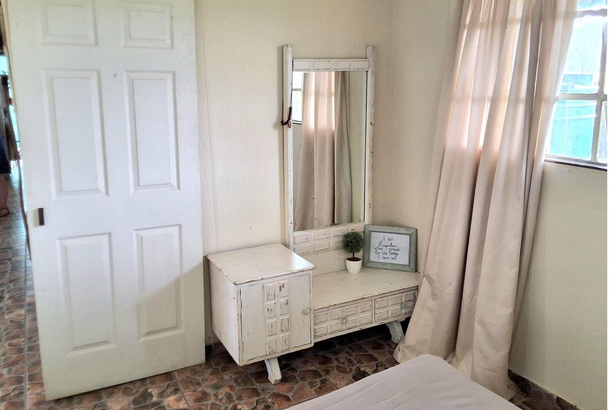 A bedroom interior featuring tiled flooring and a window with curtains.