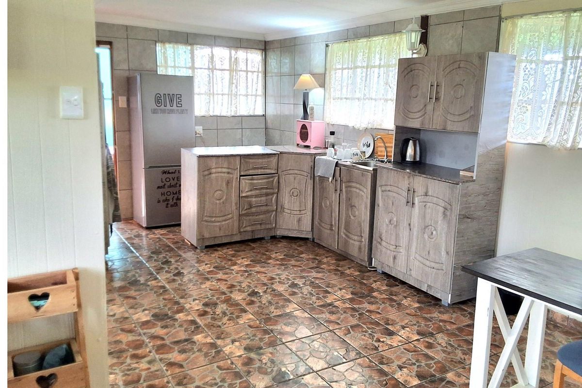 A functional kitchen featuring wood-look cabinetry, stone-effect countertops, and tiled flooring, offering a practical layout with ample storage and preparation space.