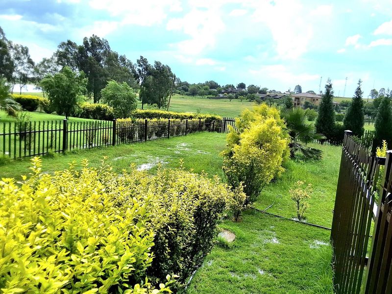 A spacious, fenced garden area featuring established landscaping and open views of the surrounding neighborhood.
