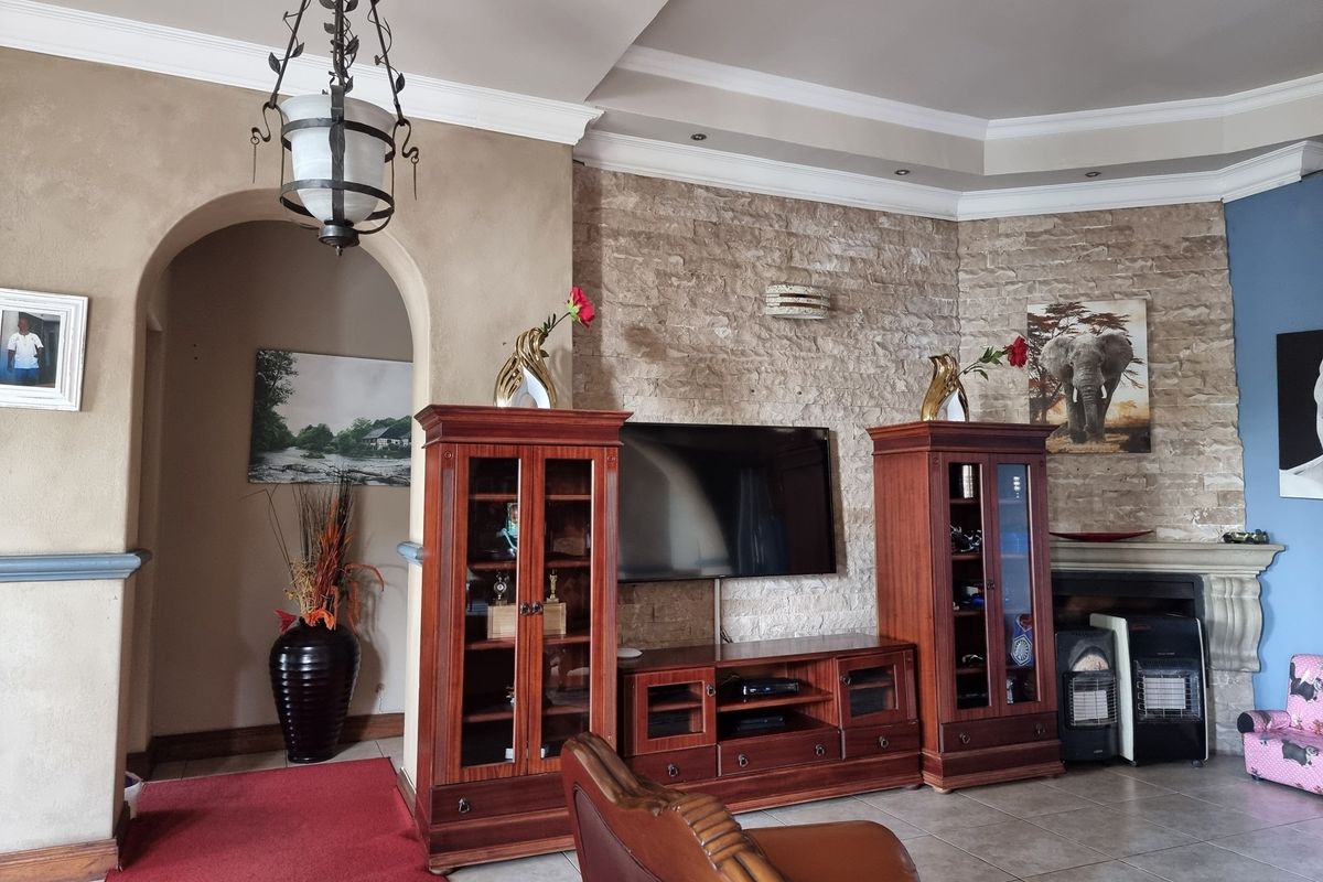A living room featuring a textured stone accent wall, an elegant archway, recessed ceiling lighting, and tiled flooring.