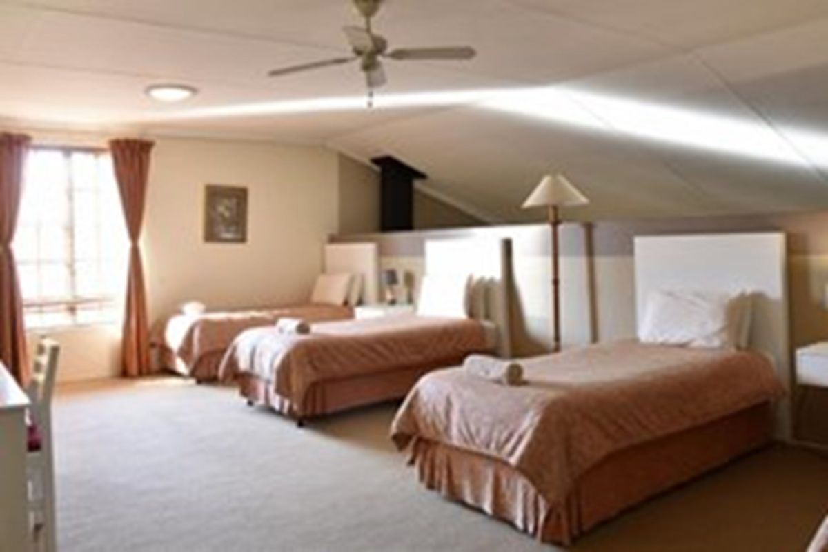 Spacious bedroom featuring a sloped ceiling, ceiling fan, and recessed lighting, providing a comfortable and functional sleeping area.