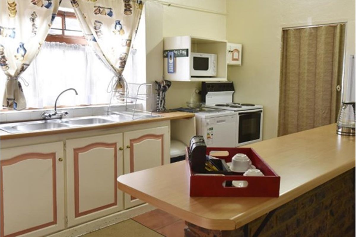 A functional kitchen featuring dated cabinetry, a double basin sink, and a breakfast counter, offering potential for a modern renovation.