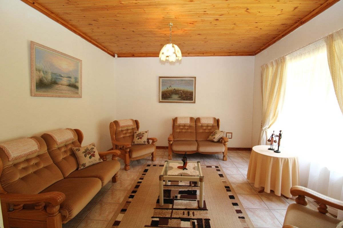A living room featuring a traditional timber-clad ceiling and tiled flooring, offering a warm and classic aesthetic.