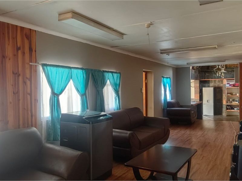 Spacious open plan living area featuring wood-look flooring and wood paneling accents, leading through to a secondary kitchen or utility space.