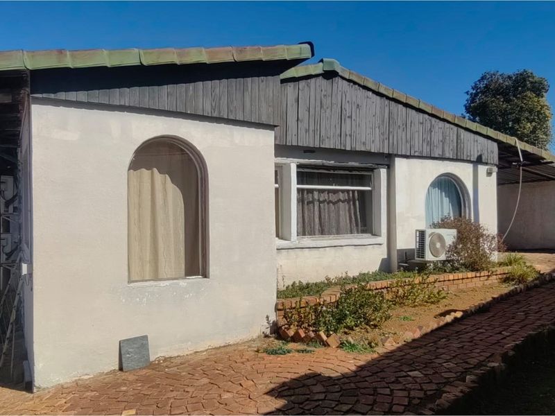 Exterior view of the property featuring a brick paved walkway, arched windows, and timber cladding under a tiled roof.