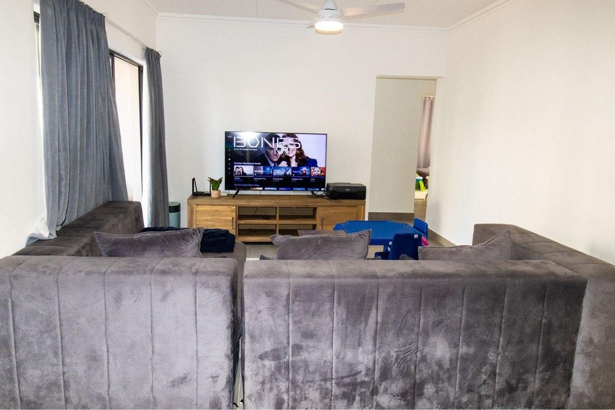 A comfortable living room featuring tiled flooring, a ceiling fan, and sliding glass doors providing access to the outdoor area.