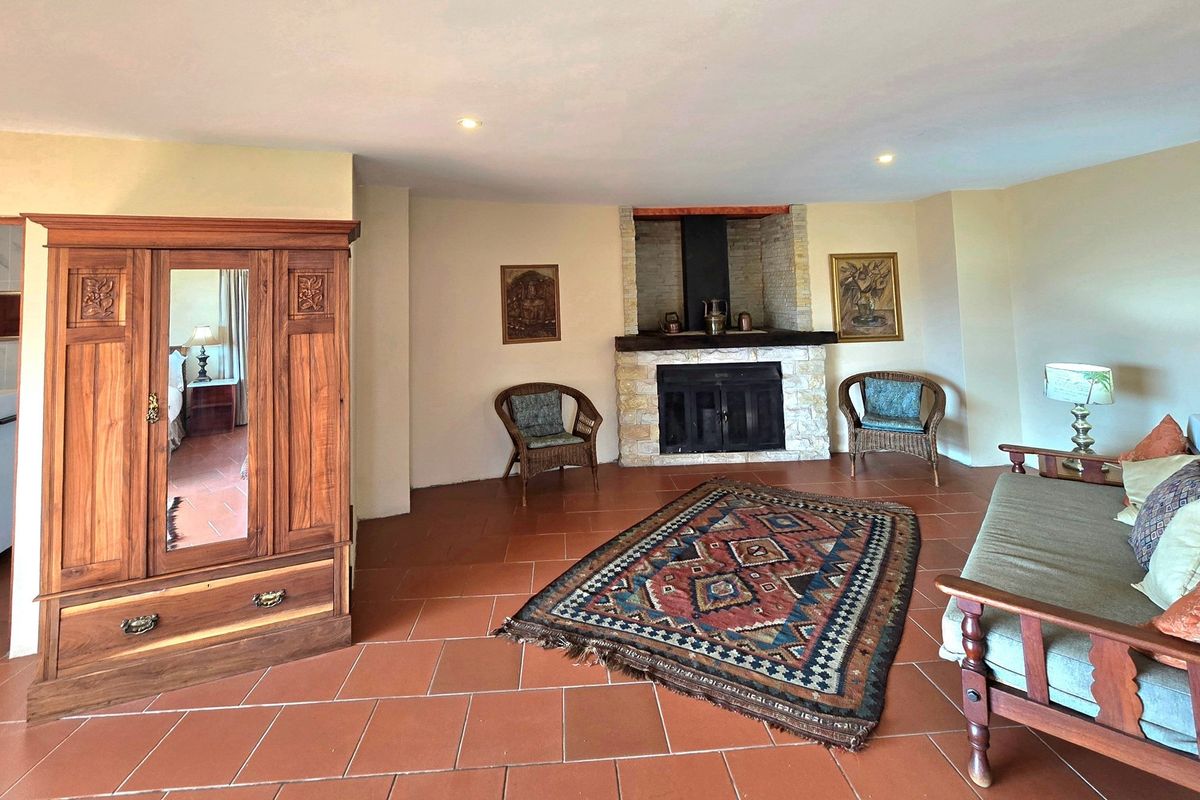 Spacious living room featuring terracotta floor tiles and a prominent stone-clad fireplace with a built-in hearth and chimney breast.