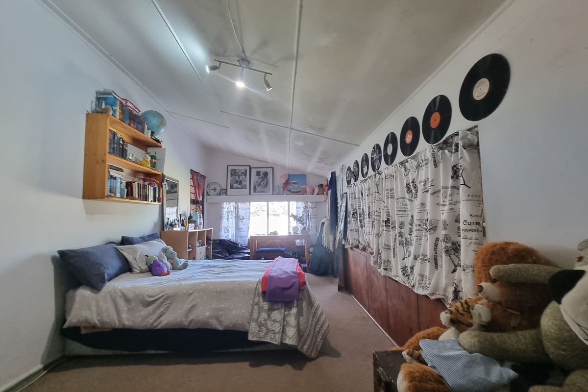 A bedroom featuring a raked ceiling, built-in wooden cabinetry, and a wall-mounted shelving unit.