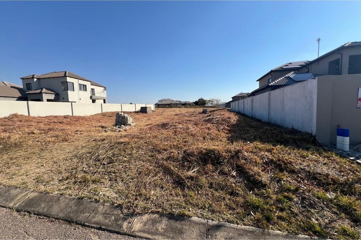 A vacant residential plot of land featuring perimeter boundary walls, situated in a developed neighborhood with street access.