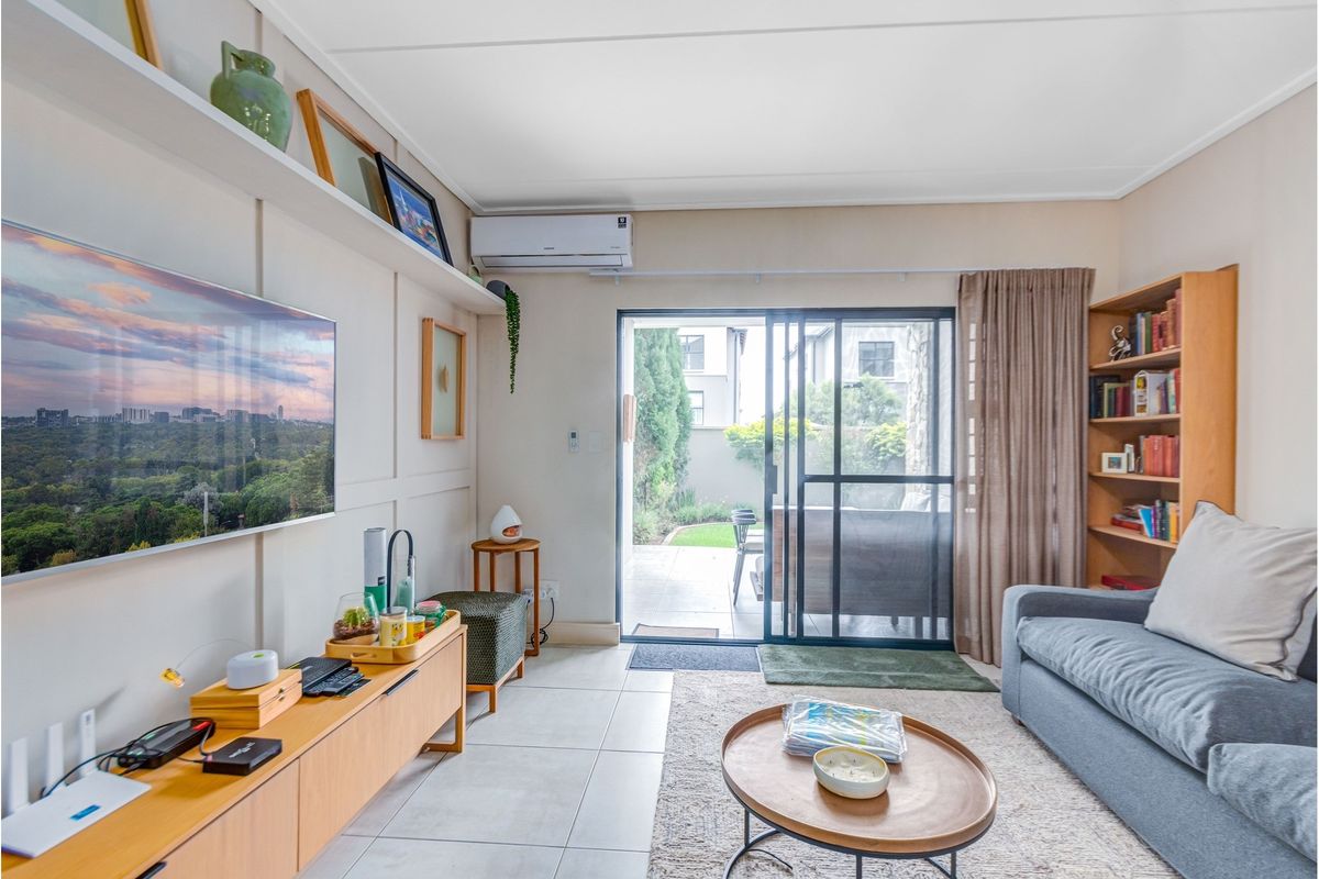 A bright living room featuring tiled floors, wall paneling, built-in shelving, and a sliding glass door providing direct access to the patio.
