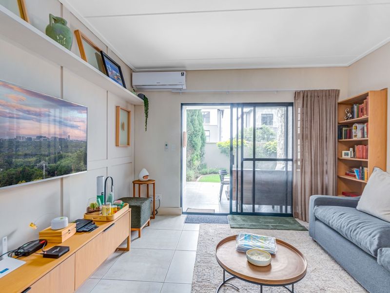 A bright living room featuring tiled floors, wall paneling, built-in shelving, and a sliding glass door providing direct access to the patio.