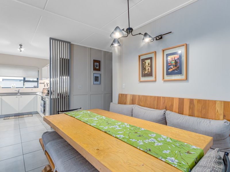 Modern open-plan kitchen and dining area featuring sleek cabinetry, tiled floors, and a decorative slatted partition between the functional kitchen and dining space.