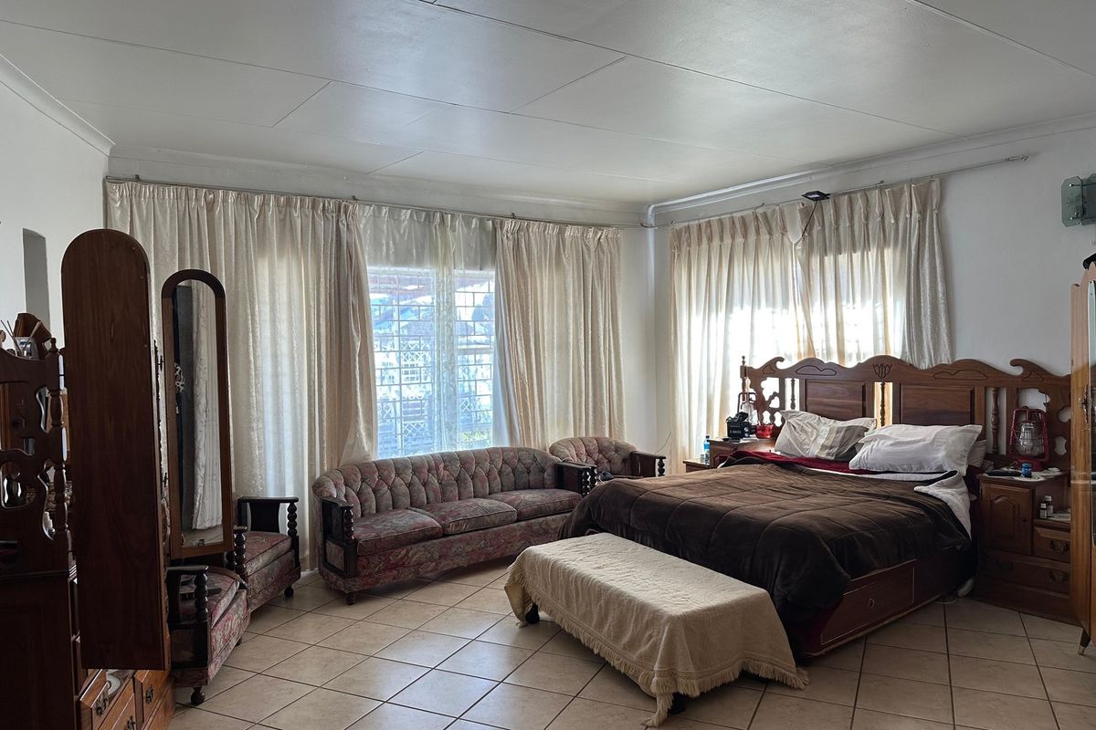 Spacious bedroom featuring tiled flooring and large windows with curtain tracks, offering a bright and functional living space.