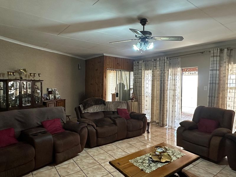 A spacious living room featuring tiled flooring, a ceiling fan, and sliding glass doors providing access to the outdoor area.