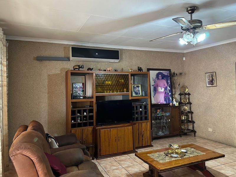 A living room featuring tiled flooring, a ceiling fan, and a wall-mounted split-system air conditioner.