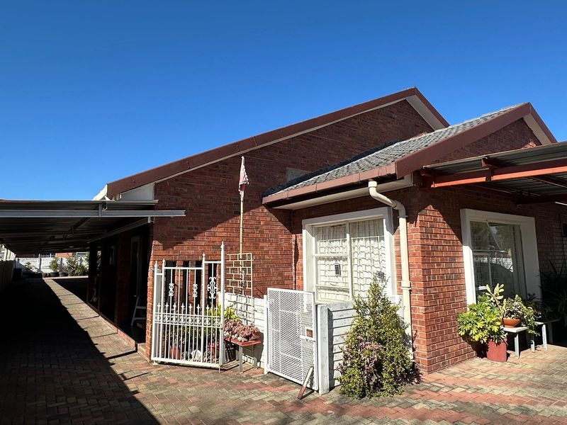 A brick-faced residential property featuring a paved driveway, integrated carport, and secure gated access with security bars on windows.