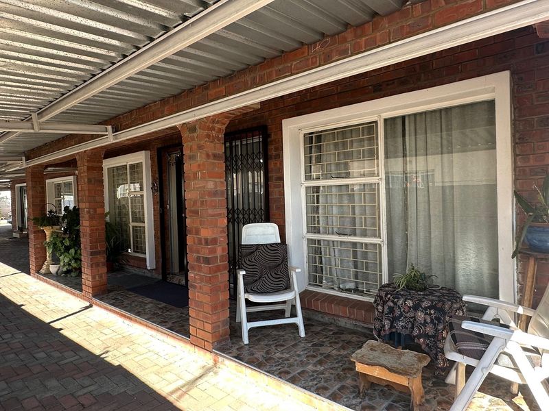 A covered patio area featuring exposed brick pillars, security gates, and tiled flooring, providing a functional outdoor space.