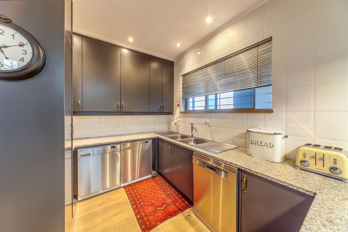 A functional kitchen featuring dark cabinetry, granite countertops, a double stainless steel sink, and integrated dishwasher space.
