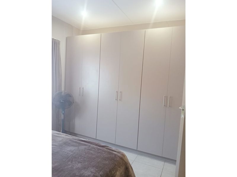 A bedroom featuring neutral-toned built-in cupboards, tiled flooring, and recessed ceiling lighting.