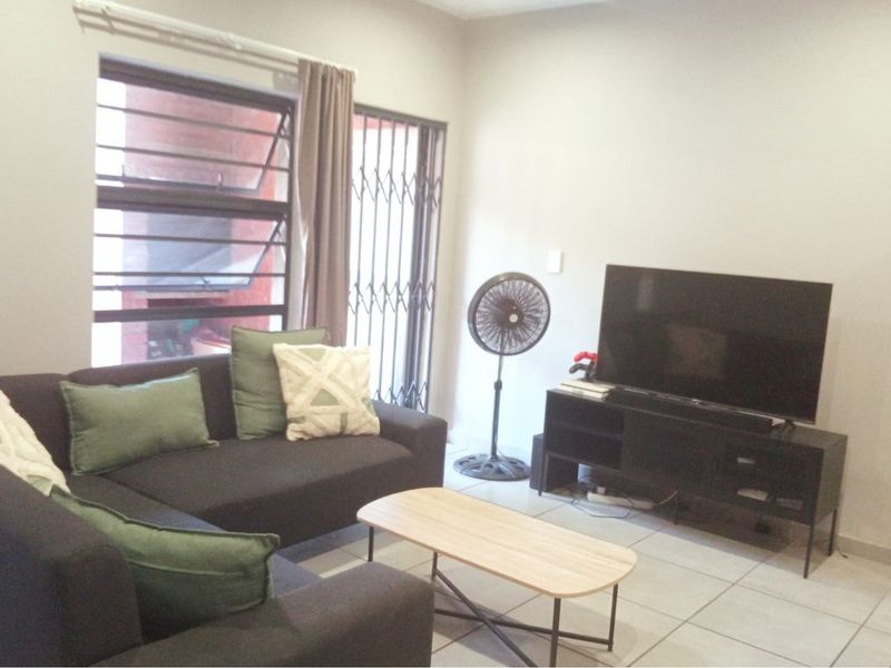 A living room featuring tiled flooring, a security gate, and a window with natural light.