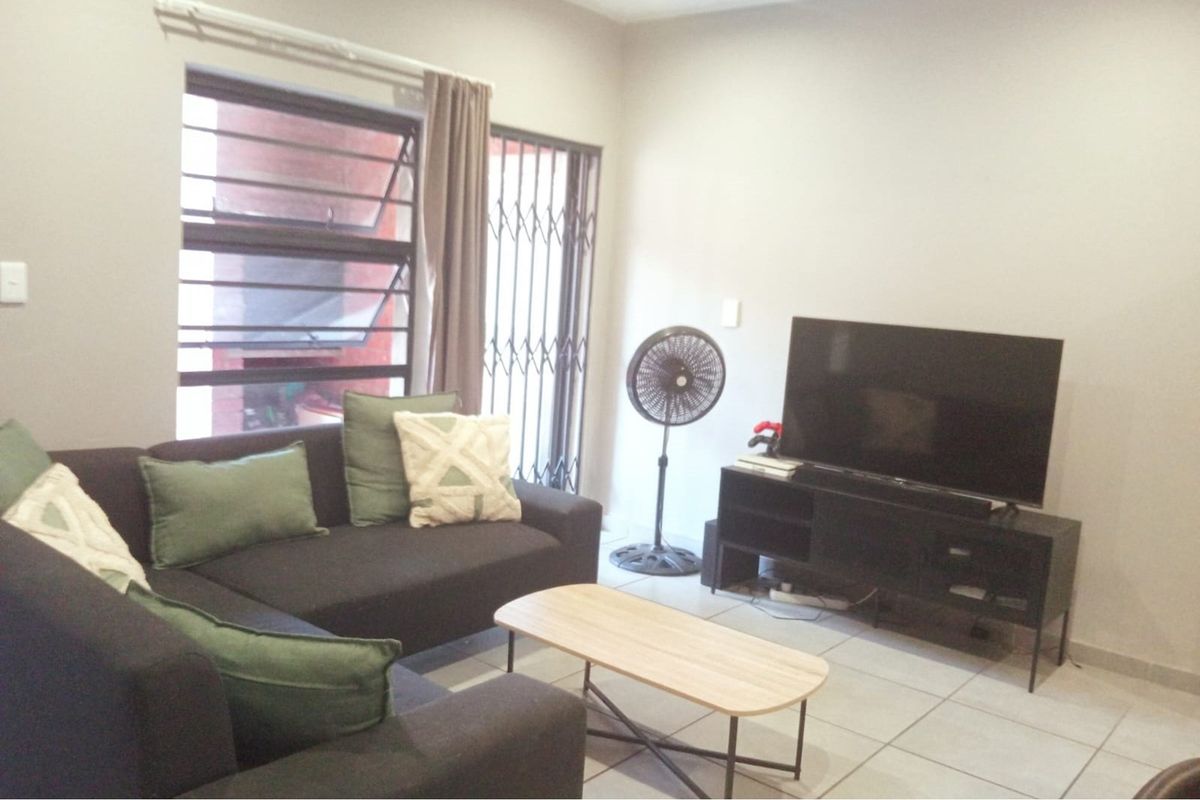 A living room featuring tiled flooring, a security gate, and a window with natural light.