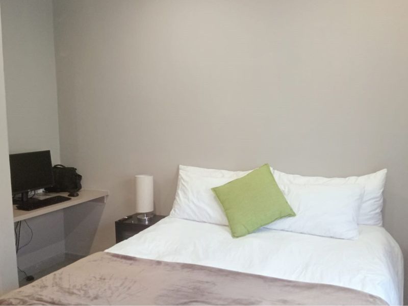 A functional bedroom featuring a built-in desk area and neutral wall finishes, providing a practical space for rest and work.