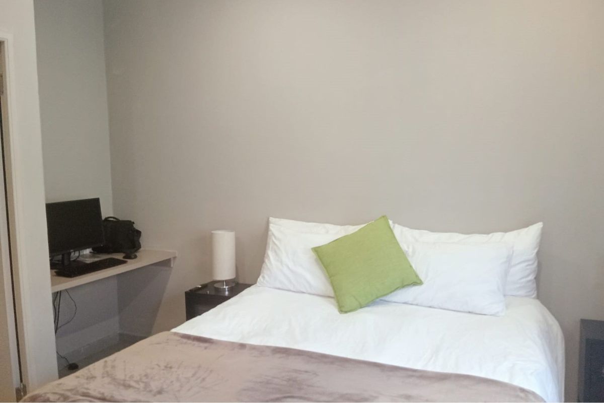 A functional bedroom featuring a built-in desk area and neutral wall finishes, providing a practical space for rest and work.