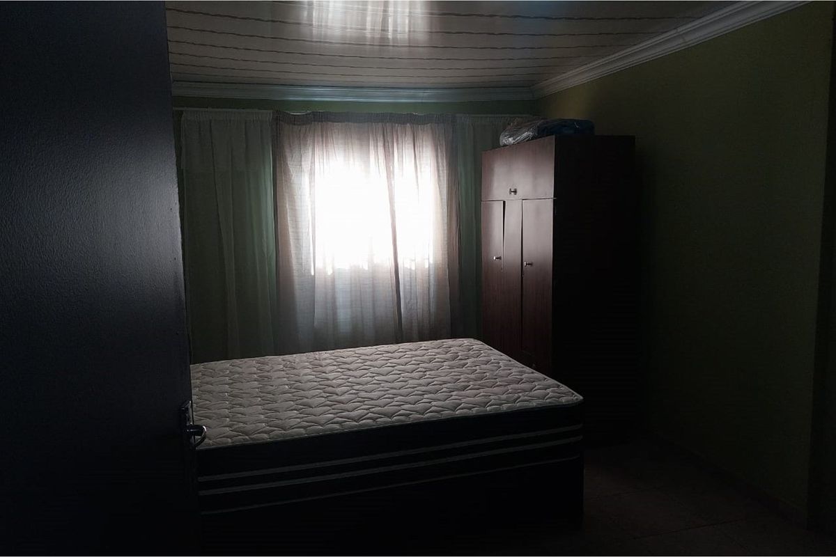 A bedroom featuring a window with curtains and a ceiling with decorative paneling.