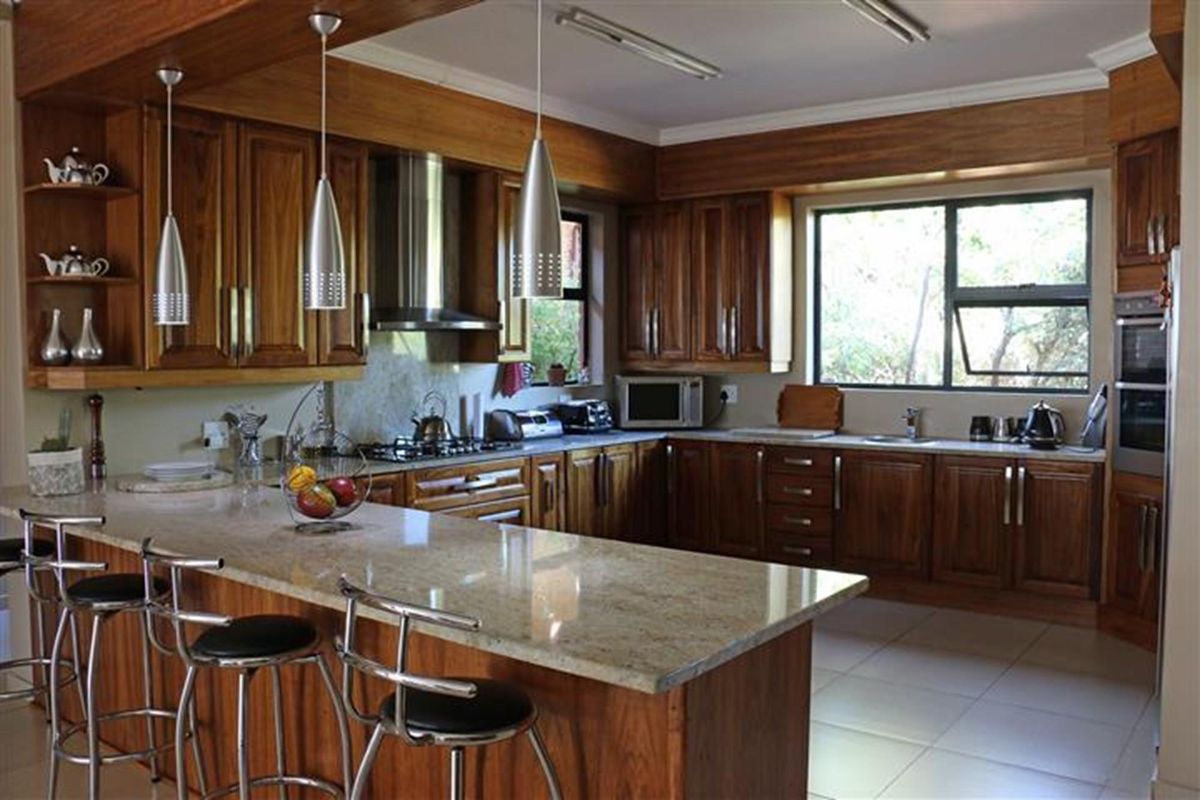 A well-appointed kitchen featuring solid wood cabinetry, granite countertops, a breakfast bar, built-in oven, and stainless steel extractor fan.