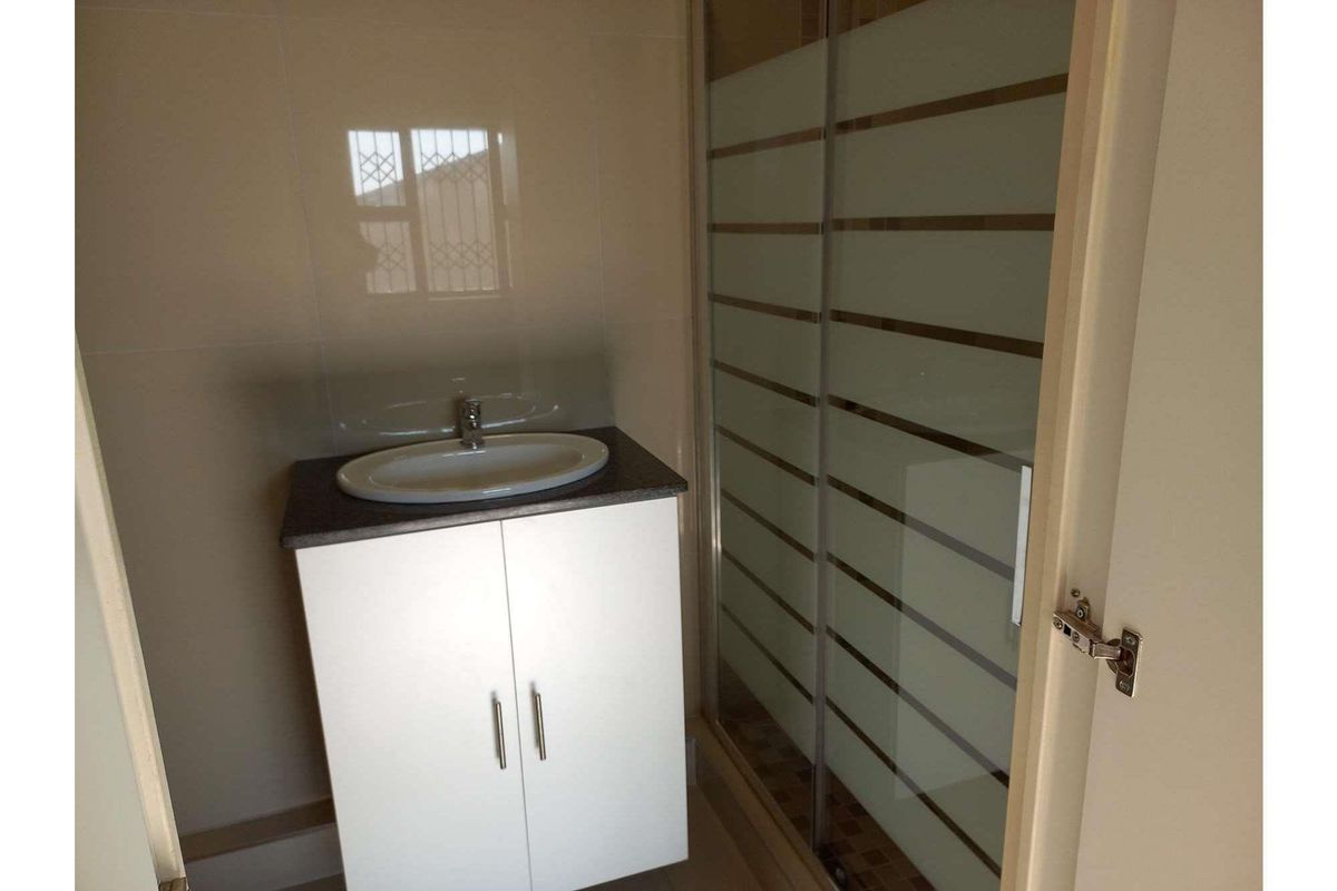 A compact bathroom featuring a modern vanity with a basin and a separate shower enclosure with frosted glass sliding doors.