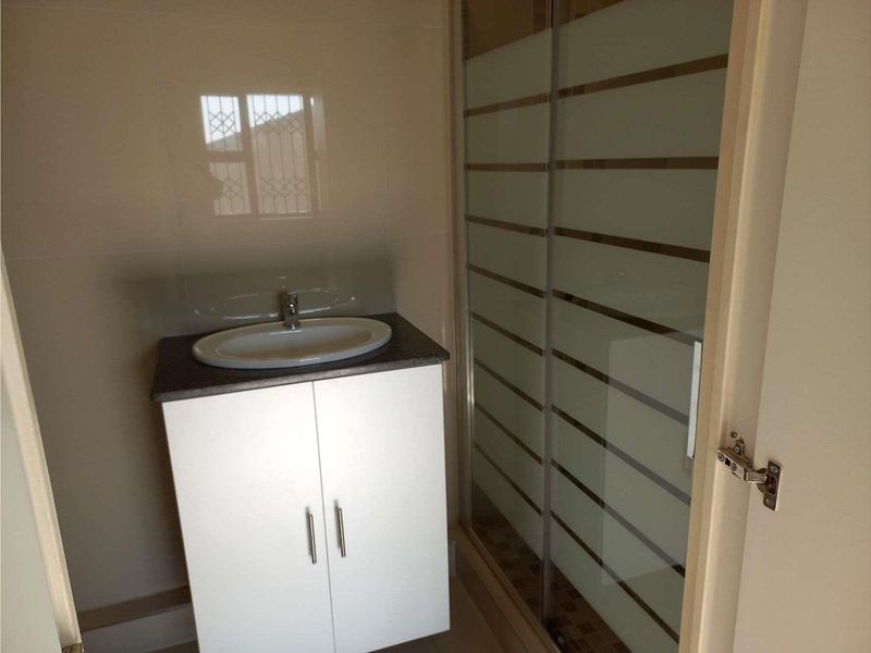 A clean, functional bathroom featuring a modern vanity with an integrated basin and a separate shower enclosure with frosted glass doors.