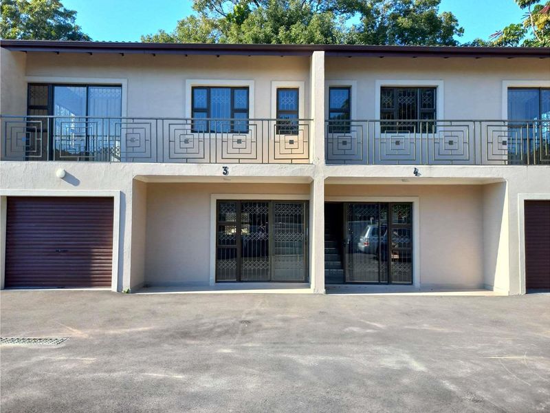 Front elevation of a two-story residential building featuring metal security gates, balcony railings, sliding glass doors, and integrated garage access.
