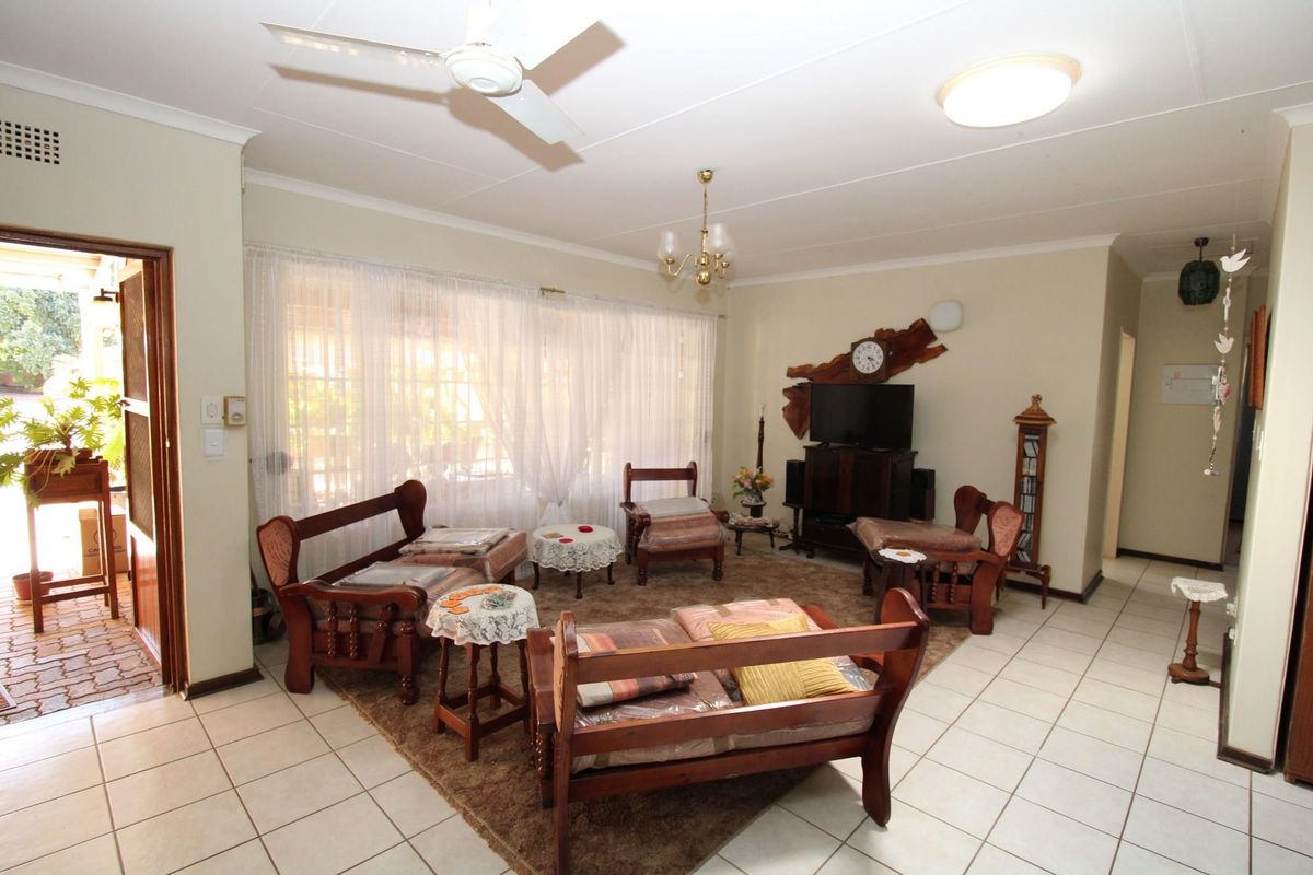 A spacious living room featuring tiled flooring, a ceiling fan, and direct access to an outdoor patio area.