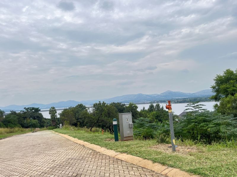 A view of a paved residential driveway leading towards a scenic landscape with water and mountain views.