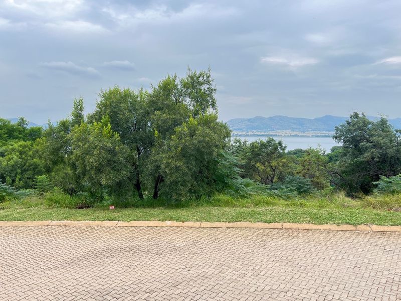 A view of the vacant residential land featuring established trees and a scenic outlook towards the distant mountains and water.