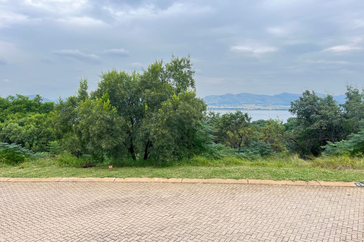 A view of the vacant residential land featuring established trees and a scenic outlook towards the distant mountains and water.