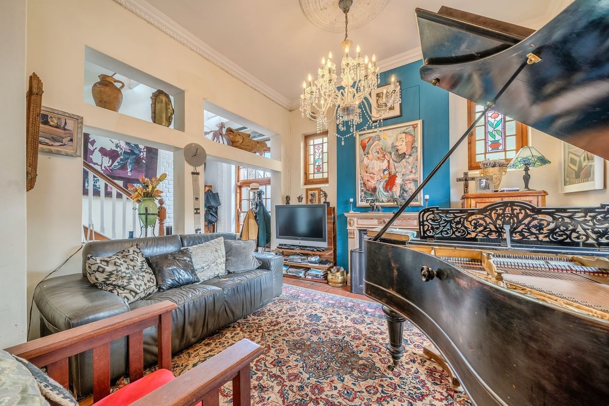 A character-filled living room featuring a decorative fireplace, ornate crystal chandelier, built-in wall niches, and stained glass window accents.