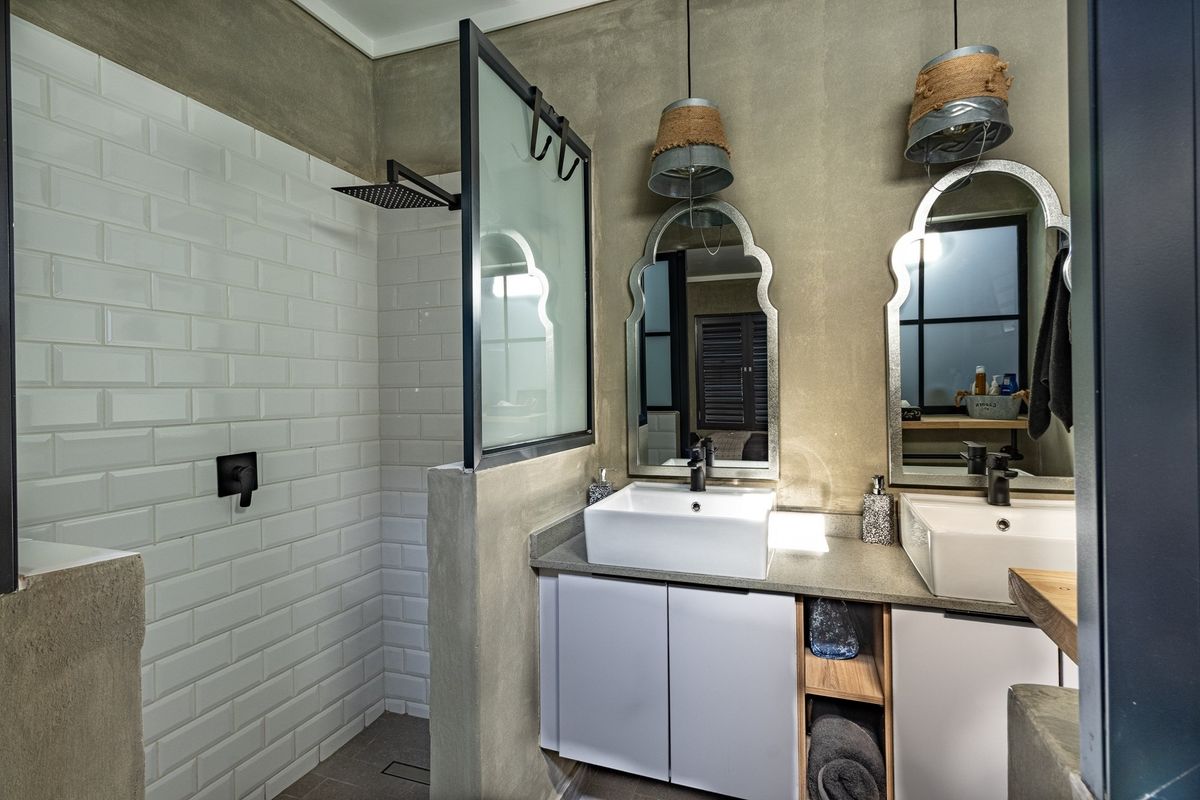 Modern bathroom featuring a double vanity with vessel sinks, a walk-in shower with white subway tiles, and industrial-style lighting fixtures.