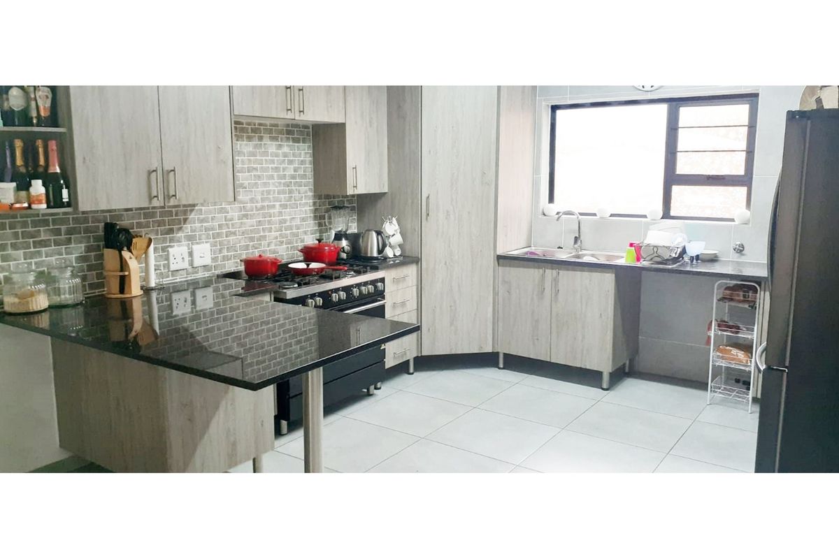Modern kitchen featuring light wood-grain cabinetry, granite countertops, a subway tile backsplash, and a built-in gas stove with an extractor fan.