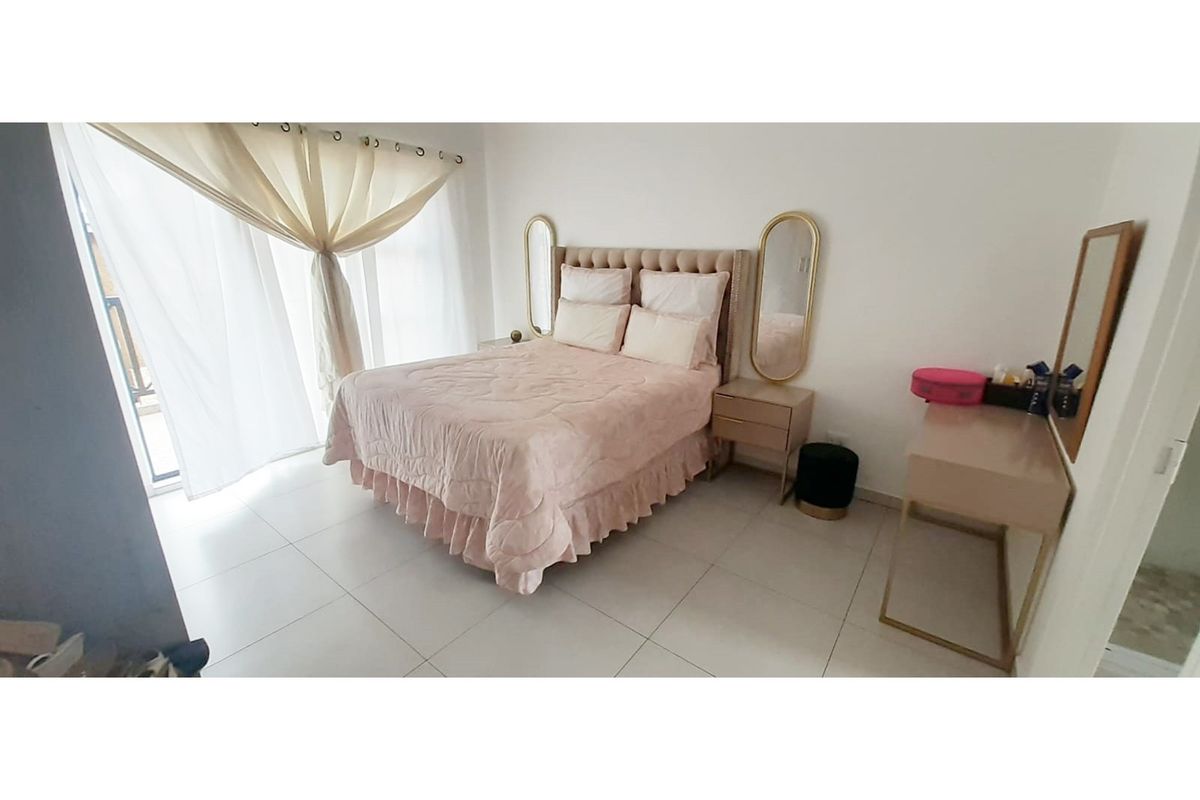 A bright bedroom featuring large sliding glass doors that provide access to a balcony, complemented by neutral floor tiles.