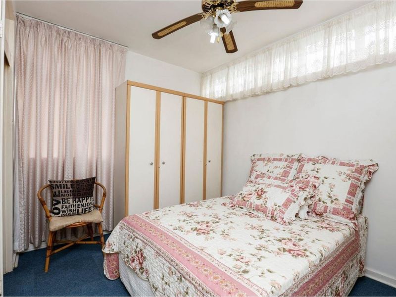 A bedroom featuring a built-in wardrobe, a ceiling fan, and carpeted flooring.