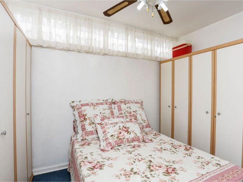 A bedroom featuring built-in wardrobes and a ceiling fan, providing functional storage and overhead lighting.