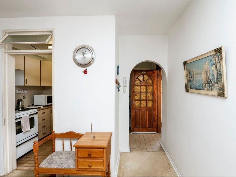 A view of the apartment hallway featuring an arched doorway leading to the entrance and a glimpse into the adjacent kitchen area.