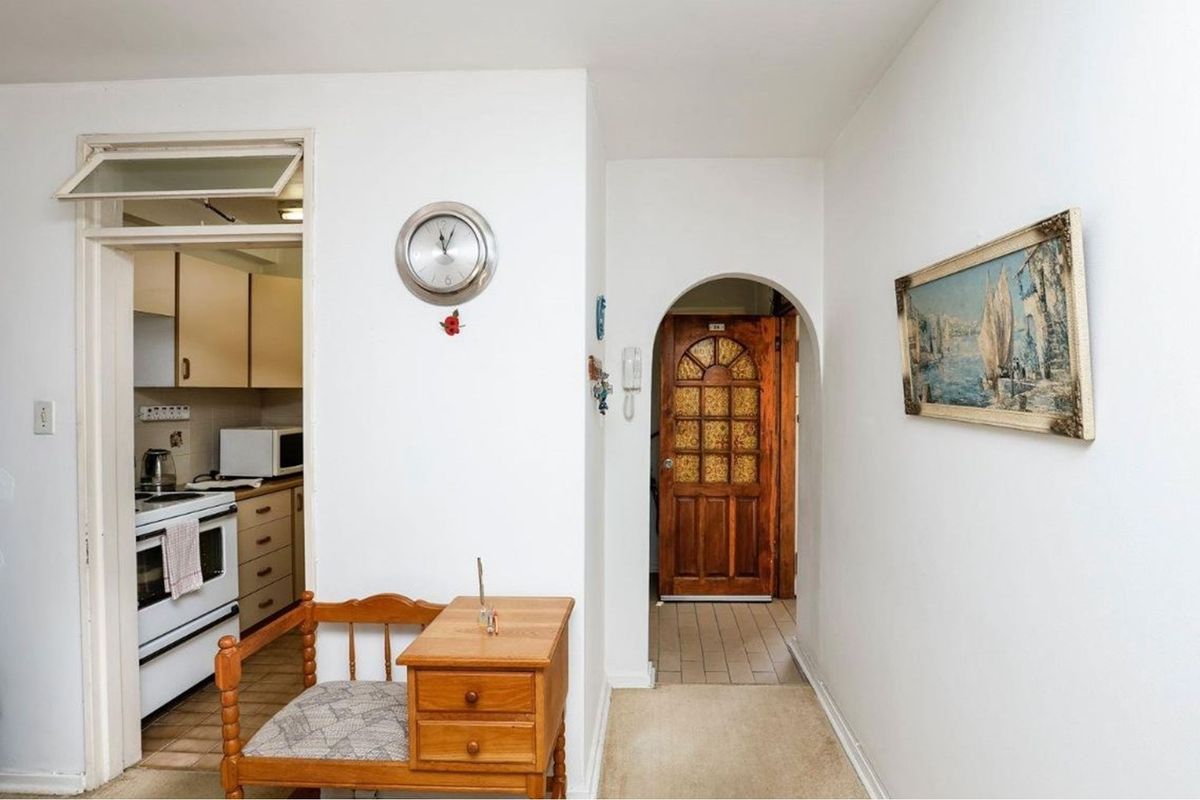 A view of the apartment hallway featuring an arched doorway leading to the entrance and a glimpse into the adjacent kitchen area.