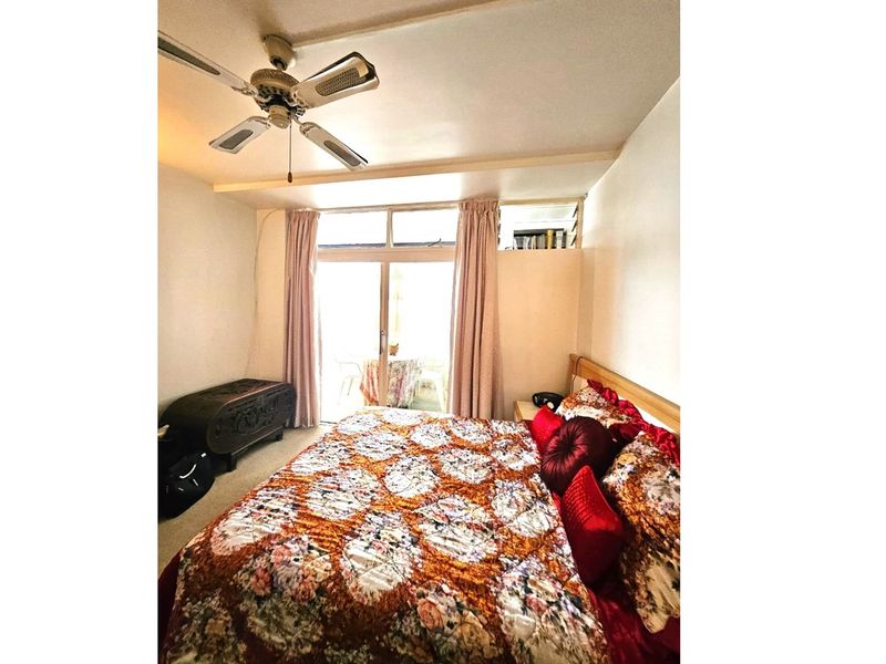 A bedroom featuring a ceiling fan and sliding glass doors that provide access to an outdoor balcony area.